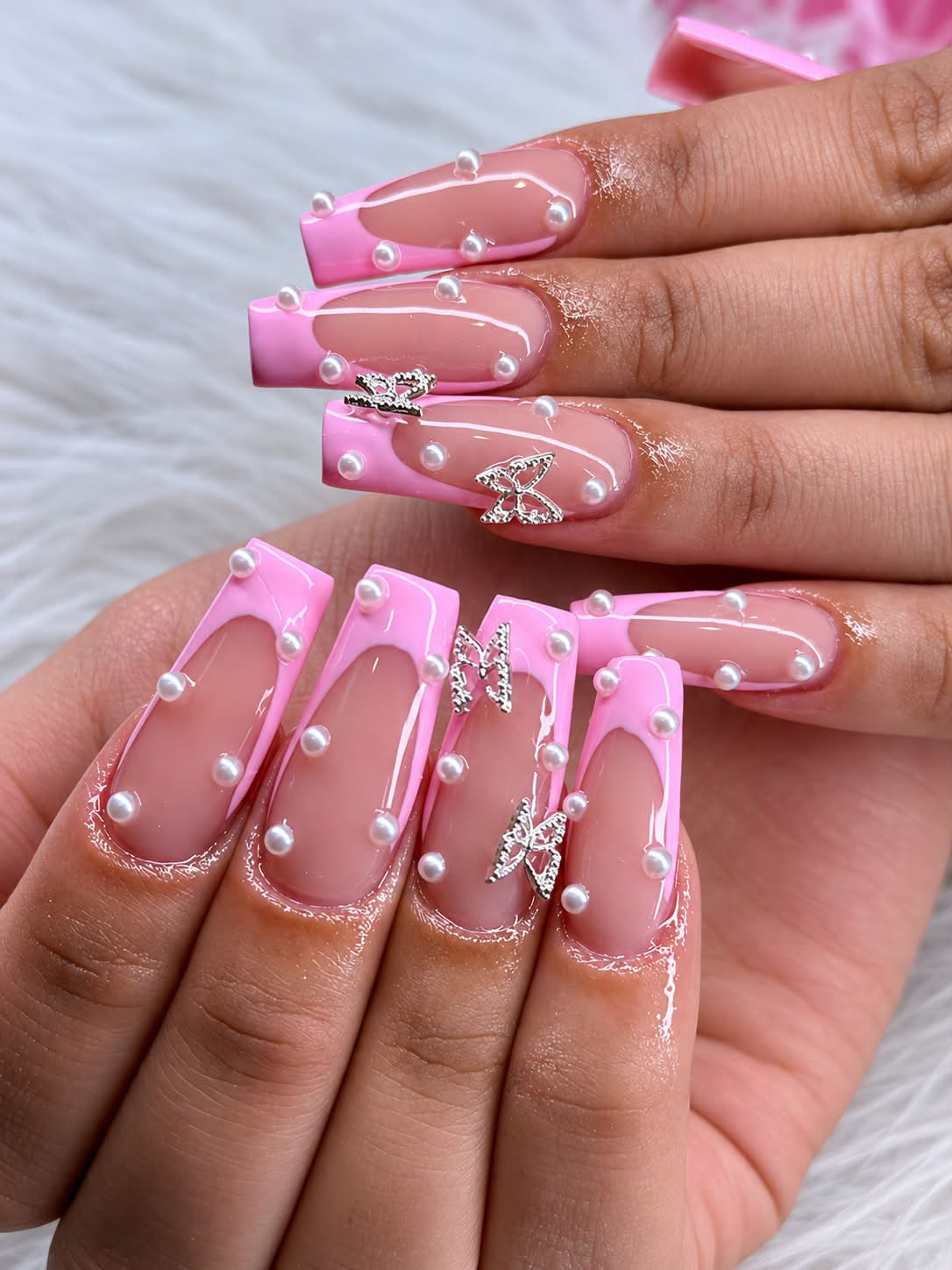 Uñas rosadas con perlas y mariposas